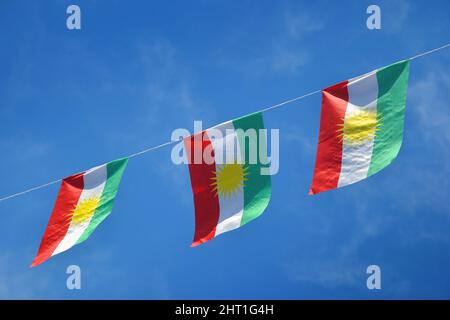 Irakische kurdische Flagge, drei nebeneinander am blauen Himmel. Stockfoto