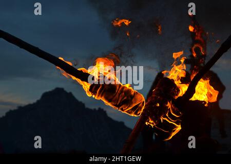 Detail von Flammen und Rauchbrennern. Blick in der Dämmerung, Dunkelheit, im Hintergrund Berge. Stockfoto