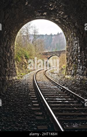 Ausgang des Vintage-Eisenbahnstollen mit Blick auf eine Steinbrücke. Bahnreisen im englischen Stil. Stockfoto