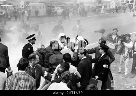 Dreharbeiten zum MGN-Film „Grand Prix“ bei Brands Hatch in Kent im Juli 1966. Schauspieler James Garner ist der amerikanische Grand-Prix-Fahrer Pete Aron, der von seinem Jordan-BRM-Rennteam gefeuert wird und für das japanische Yamura-Team fährt. Im Bild: Während der Dreharbeiten musste James Garner seinen Rennwagen (kein Stunt-Mann) für 1/2 eine Meile rund um Brands Hatch Circuit fahren, während er in Brand war. James hielt kurz nach der Ziellinie an und sprang aus dem Cockpit, als Flammen das Auto umschlingen. Feuerwehrmänner waren bereit, die Flammen zu löschen. James Garner ist während der Dreharbeiten zu diesem Film für £1million versichert. Stockfoto