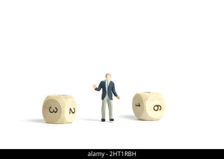Miniatur Menschen Spielzeug Figur Fotografie. Ein zuckender Geschäftsmann, der mitten in Holzwürfeln steht. Isoliert auf weißem Hintergrund. Bildfoto Stockfoto