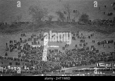 Aberfan - 27.. Oktober 1966 das riesige Kreuz von Kränzen auf dem Aberfan-Friedhof am Hang, während die Beerdigungen stattfinden. Die Katastrophe von Aberfan war ein katastrophaler Einsturz einer kollidierenden Beute im walisischen Dorf Aberfan, in der Nähe von Merthyr Tydfil. Er wurde durch eine Ansammlung von Wasser im angesammelten Fels und Schiefer verursacht, die plötzlich in Form von Schlamm bergab zu rutschen begann und am 21.. Oktober 1966 die Pantglas Junior School darunter verschlang und 116 Kinder und 28 Erwachsene tötete. Das ursprüngliche Schulgelände ist heute ein Gedenkgarten. Aufgenommen am 27.. Oktober 1966The Ereignisse am Freitag, 21. Oktob Stockfoto