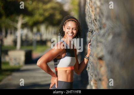 Sie denken bereits an den nächsten Lauf. Kurzer Schuss einer attraktiven jungen Frau, die durch die Stadt läuft. Stockfoto