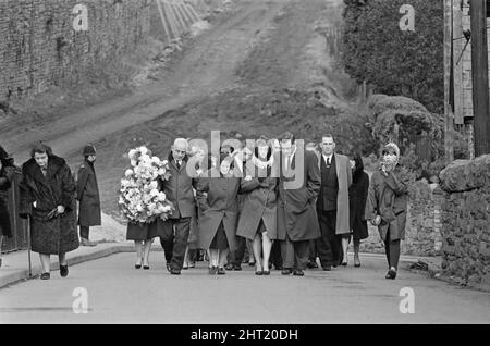 Aberfan - 27.. Oktober 1966. Trauernde gehen durch die Straßen, auf ihrem Weg zum Friedhof, um an der Massenbesetzung für die Opfer der Schlammrutsche-Katastrophe von Aberfan teilzunehmen. D ie Katastrophe von Aberfan war ein katastrophaler Zusammenbruch einer kollidierenden Beute im walisischen Dorf Aberfan, in der Nähe von Merthyr Tydfil. Er wurde durch eine Ansammlung von Wasser im angesammelten Fels und Schiefer verursacht, die plötzlich in Form von Schlamm bergab zu rutschen begann und am 21.. Oktober 1966 die Pantglas Junior School darunter verschlang und 116 Kinder und 28 Erwachsene tötete. Das ursprüngliche Schulgelände ist heute ein Gedenkgarten. Bild Stockfoto