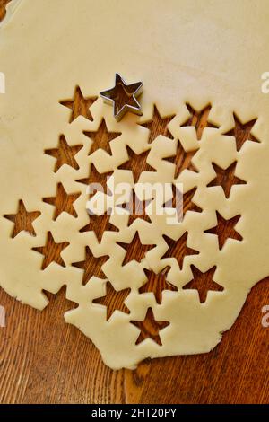 Roher Zucker-Keksteig, der mit einem Stern-Keksschneider auf der Theke ausgerollt wird, für Weihnachten oder andere Feiertage, die zu Hause, Browntown, Wisconsin, USA, gebacken werden Stockfoto