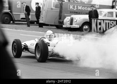 Dreharbeiten zum MGN-Film „Grand Prix“ bei Brands Hatch in Kent im Juli 1966. Schauspieler James Garner ist der amerikanische Grand-Prix-Fahrer Pete Aron, der von seinem Jordan-BRM-Rennteam gefeuert wird und für das japanische Yamura-Team fährt. Im Bild: Während der Dreharbeiten musste James Garner seinen Rennwagen (kein Stunt-Mann) für 1/2 eine Meile rund um Brands Hatch Circuit fahren, während er in Brand war. James hielt kurz nach der Ziellinie an und sprang aus dem Cockpit, als Flammen das Auto umschlingen. Feuerwehrmänner waren bereit, die Flammen zu löschen. James Garner ist während der Dreharbeiten zu diesem Film für £1million versichert. Stockfoto