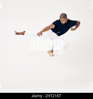 Die Gewohnheit des Beharrens ist die Gewohnheit des Sieges. Studioaufnahme eines jungen Kampfkünstlers, der praktiziert. Stockfoto