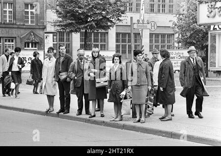 Szenen in Ost-Berlin, vier Jahre nach Beginn der Arbeiten am Bau der Berliner Mauer, die Ost und West trennt. In der Berliner Innenstadt warten Einheimische auf den Bus. 26. Mai 1965. Stockfoto