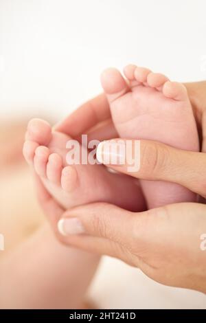 Winzig kleine Füße. Nahaufnahme einer Mutter, die ihre Babynahrung hält. Stockfoto