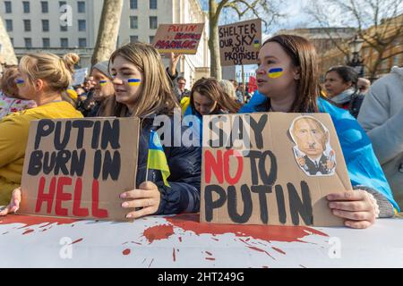 London, Großbritannien. Februar 2022. Demonstranten versammeln sich in einer britischen Stadt, um gegen die russische Aggression zu protestieren und ihre Solidarität mit der Ukraine auszudrücken. Demonstranten halten Schilder, die Wladimir Putin verurteilen, mit Slogans wie "PUTIN BRENNT IN DER HÖLLE" und "SAG NEIN ZU PUTIN". Ukrainische Flaggenfarben sind auf Gesichtern gemalt, und Plakate fordern internationalen Schutz und internationale Maßnahmen. Der Protest hebt öffentliche Meinungsverschiedenheiten und politischen Aktivismus als Reaktion auf den Krieg in der Ukraine hervor. Hunderte versammeln sich zu einem Protest, um Solidarität mit der Ukraine vor der Downing Street zu zeigen. Penelope Barritt/Alamy Live News Stockfoto