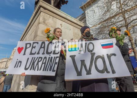 London, Großbritannien. Februar 2022. Demonstranten versammeln sich vor einem Denkmal mit Sonnenblumen und Schildern mit der Aufschrift „Frieden in der Ukraine“ und „kein Krieg“, wobei ukrainische und russische Fahnen abgebildet sind. Der Protest fordert ein Ende des Konflikts und fördert die Solidarität mit der Ukraine. Hunderte versammeln sich zu einem Protest, um Solidarität mit der Ukraine vor der Downing Street zu zeigen. Penelope Barritt/Alamy Live News Stockfoto