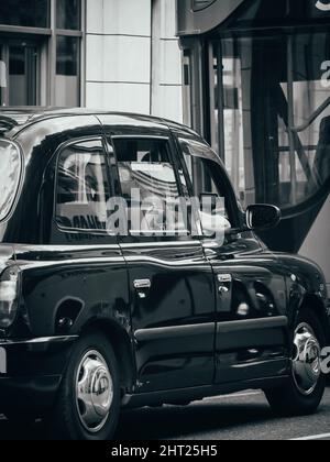 Graustufenaufnahme eines Taxis, das auf der Straße in London, England, geparkt ist Stockfoto