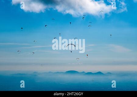 Gleitschirme, die vom Monte Grappa starten und über die Südhänge des Berges, hoch über der Ebene fliegen. Stockfoto