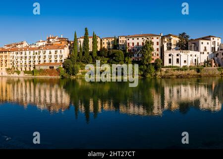 Fassaden mittelalterlicher Häuser von Bassano del Grappa, die sich im Fluss Brenta spiegeln. Stockfoto