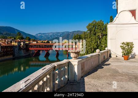 Die Brücke Ponte Vecchio, Ponte degli Alpini, die über den Fluss Brenta in Bassano del Grappa führt, Ausläufer des Monte Grappa in der Ferne. Stockfoto