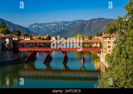 Die Brücke Ponte Vecchio, Ponte degli Alpini, die über den Fluss Brenta in Bassano del Grappa führt, Ausläufer des Monte Grappa in der Ferne. Stockfoto