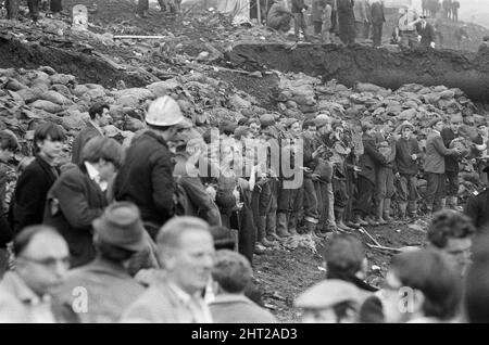 Aberfan - 21.. Oktober 1966 Männer stellen sich an Sandsäcken, die mit dem Schlamm am Hang gefüllt sind, abseits der Katastrophenzone an. Die Katastrophe von Aberfan war ein katastrophaler Einsturz einer kollidierenden Beute im walisischen Dorf Aberfan, in der Nähe von Merthyr Tydfil. Er wurde durch eine Ansammlung von Wasser im angesammelten Fels und Schiefer verursacht, die plötzlich in Form von Schlamm bergab zu rutschen begann und am 21.. Oktober 1966 die Pantglas Junior School darunter verschlang und 116 Kinder und 28 Erwachsene tötete. Das ursprüngliche Schulgelände ist heute ein Gedenkgarten. Aufgenommen am 21.. Oktober 1966The Ereignisse am Freitag, 21. Oktob Stockfoto