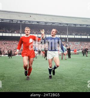 Das 1966 FA Charity Shield Merseyside Derby-Spiel zwischen Liverpool und Everton im Goodison Park. Vor dem Spiel haben Roger Hunt, Alan Ball und Ray Wilson die Weltmeisterschaft, den FA Cup und die Football League Trophy um den Goodison Park geführt. Liverpool gewann das Spiel mit einem Tor von 1 zu 0. Das Bild zeigt: Roger Hunt und Ray Wilson, Mitglieder des siegreichen England-Teams des Sommers, paradieren die WM-Trophäe um das Stadion. 13.. August 1966. Stockfoto