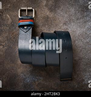 Stilvoller blauer Ledergürtel für Herren mit farbigen Schultergurten und Metallschnalle auf dunklem Hintergrund Stockfoto