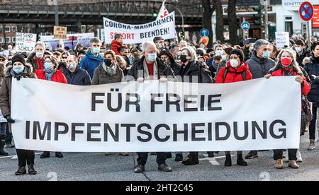 Hamburg, Deutschland. 26.. Februar 2022. Die Demonstranten stehen hinter einem Transparent mit der Aufschrift „für eine kostenlose Impfentscheidung“. Die Kritiker der Corona-Pandemieeindämmungspolitik demonstrieren in der Hansestadt unter dem Motto "Gegen Zwangsmasken und andere Corona-Eindämmungsmaßnahmen - für Selbstbestimmung, Meinungs- und Meinungsfreiheit und Demokratie". Quelle: Markus Scholz/dpa/Alamy Live News Stockfoto