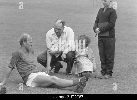 Die Vorbereitungen Englands für das WM-Finale im Juli nehmen zu. Herr Alf Ramsey, der Teammanager, hat 27 Spieler in Lilleshall, Shropshire, für 12 Tage Training versammelt. Am kommenden Freitag wird er 22 für die Continental-Tour benennen, und diese Männer, sagt er, werden „die WM-Mannschaft sein“. Das Problem ist, welche 5 auszulassen? Herr Ramsey hofft, die Antwort während der Schulung zu finden, „obwohl es die schwierigste Entscheidung sein wird, die ich je treffen musste“. Unser Foto zeigt Bobby Charlton, der mit Fans plaudert, während er eine Verschnaufpause macht.9.. Juni 1966 Stockfoto