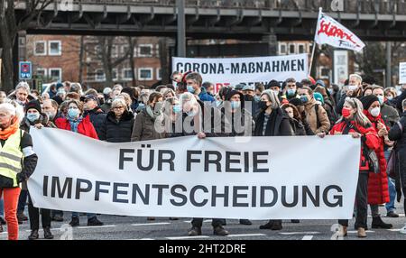 Hamburg, Deutschland. 26.. Februar 2022. Die Demonstranten stehen hinter einem Transparent mit der Aufschrift „für eine kostenlose Impfentscheidung“. Die Kritiker der Corona-Pandemieeindämmungspolitik demonstrieren in der Hansestadt unter dem Motto "Gegen Zwangsmasken und andere Corona-Eindämmungsmaßnahmen - für Selbstbestimmung, Meinungs- und Meinungsfreiheit und Demokratie". Quelle: Markus Scholz/dpa/Alamy Live News Stockfoto