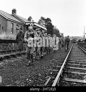 Die Jagd nach dem entflohenen Sträfling Frank Mitchell. Männer der 1. Argyll- und Sutherland-Highlanders nahmen heute an der Manhunt Teil. Jeder ist mit einem Pick-Griff bewaffnet, angeführt von dem unbewaffneten Pfeifer Paddy Pearson, und man sieht, wie sie sich in Lydford, Devon, zwischen einer Eisenbahnlinie ausbreiteten. 14.. Dezember 1966. Stockfoto