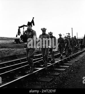 Die Jagd nach dem entflohenen Sträfling Frank Mitchell. Männer der 1. Argyll- und Sutherland-Highlanders nahmen heute an der Manhunt Teil. Jeder ist mit einem Pick-Griff bewaffnet, angeführt von dem unbewaffneten Pfeifer Paddy Pearson, und man sieht, wie sie sich in Lydford, Devon, zwischen einer Eisenbahnlinie ausbreiteten. 14.. Dezember 1966. Stockfoto