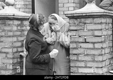 Aberfan - 21.. Oktober 1966 Eine Dame der Heilsarmee tröstet eine ältere Dame, die über die sich abzeichnenden Ereignisse in Aberfan heute verzweifelt ist. Die Katastrophe von Aberfan war ein katastrophaler Einsturz einer kollidierenden Beute im walisischen Dorf Aberfan, in der Nähe von Merthyr Tydfil. Er wurde durch eine Ansammlung von Wasser im angesammelten Fels und Schiefer verursacht, die plötzlich in Form von Schlamm bergab zu rutschen begann und am 21.. Oktober 1966 die Pantglas Junior School darunter verschlang und 116 Kinder und 28 Erwachsene tötete. Das ursprüngliche Schulgelände ist heute ein Gedenkgarten. Bild aufgenommen am 21.. Oktober 1966T Stockfoto