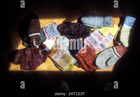 Analog ist das bunte Handwerk der gestrickten Fäustlinge auf einem Boden. Verschiedene Texturen, Muster im Set. Stockfoto