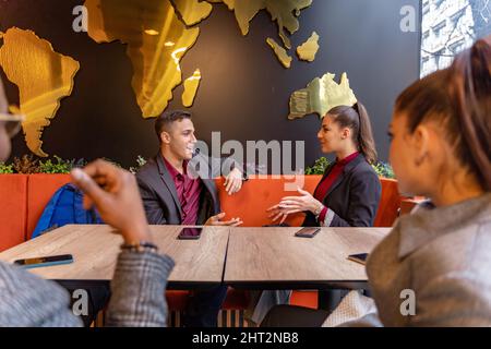 Eine Gruppe von multirassischen Geschäftsleuten lächelt und redet, während sie im Café sitzt Stockfoto