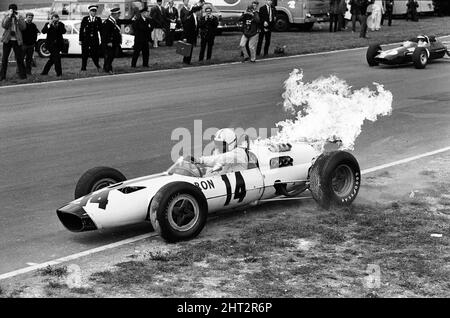 Dreharbeiten zum MGN-Film „Grand Prix“ bei Brands Hatch in Kent im Juli 1966. Schauspieler James Garner ist der amerikanische Grand-Prix-Fahrer Pete Aron, der von seinem Jordan-BRM-Rennteam gefeuert wird und für das japanische Yamura-Team fährt. Im Bild: Während der Dreharbeiten musste James Garner seinen Rennwagen (kein Stunt-Mann) für 1/2 eine Meile rund um Brands Hatch Circuit fahren, während er in Brand war. James hielt kurz nach der Ziellinie an und sprang aus dem Cockpit, als Flammen das Auto umschlingen. Feuerwehrmänner waren bereit, die Flammen zu löschen. James Garner ist während der Dreharbeiten zu diesem Film für £1million versichert. Stockfoto