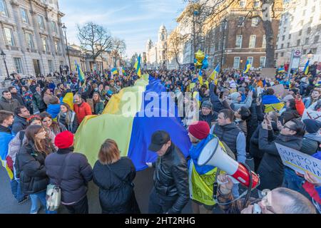 London, Großbritannien. Februar 2022. Eine große Menschenmenge versammelt sich auf Whitehall im Zentrum Londons zu einer öffentlichen Demonstration zur Unterstützung der Ukraine. Die Teilnehmer halten eine riesige ukrainische Flagge und kleinere Banner, mit Reden und Gesängen, die durch Megaphone verstärkt werden. Demonstranten laufen mit einer riesigen ukrainischen Flagge entlang Whitehall. Penelope Barritt/Alamy Live News Stockfoto