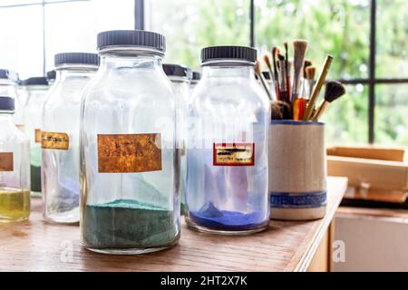 Alte Glasröhren voller Farbfarben, im Hintergrund sind Paint Brushes zu sehen Stockfoto