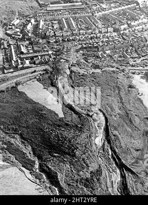 Aberfan, Südwales. Bild aufgenommen 1pm am 21.. Oktober 1966. Das aus der Luft aufgenommene Bild zeigt die Bergspitze und den Minenraub, der den Hang hinunter gerutscht hat und die Schule und einen Teil der Stadt zerstört hat. Die Katastrophe von Aberfan war ein katastrophaler Einsturz einer kollidierenden Beute im walisischen Dorf Aberfan, in der Nähe von Merthyr Tydfil, am Freitag, dem 21.. Oktober 1966. Er wurde durch eine Ansammlung von Wasser im angesammelten Fels und Schiefer verursacht, die plötzlich in Form von Schlamm bergab zu rutschen begann und am 21.. Oktober 1966 die Pantglas Junior School darunter verschlang und 116 Kinder tötete Stockfoto