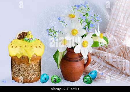 Osterkuchen mit Zuckerhuhn und Wachteleiern, einem Strauß Anemonen und Vergissmeinnicht in einer Tonvase auf hellem Hintergrund Stockfoto