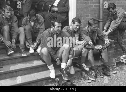 Die Vorbereitungen Englands für das WM-Finale im Juli nehmen zu. Herr Alf Ramsey, der Teammanager, hat 27 Spieler in Lilleshall, Shropshire, für 12 Tage Training versammelt. Am kommenden Freitag wird er 22 für die Continental-Tour benennen, und diese Männer, sagt er, werden „die WM-Mannschaft sein“. Das Problem ist, welche 5 auszulassen? Herr Ramsey hofft, die Antwort während der Schulung zu finden, „obwohl es die schwierigste Entscheidung sein wird, die ich je treffen musste“. Unser Foto zeigt einige der Spieler, die ihre Stiefel für eine Trainingseinheit aufsetzen. 9.. Juni 1966 Stockfoto