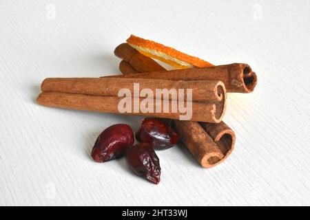 Zimt, getrocknete Orange und getrocknete Hagebutten auf weißem Hintergrund. Stockfoto