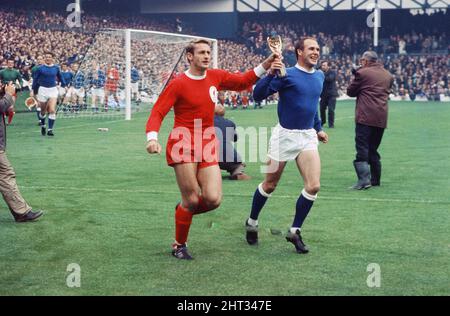 Das 1966 FA Charity Shield Merseyside Derby-Spiel zwischen Liverpool und Everton im Goodison Park. Vor dem Spiel haben Roger Hunt, Alan Ball und Ray Wilson die Weltmeisterschaft, den FA Cup und die Football League Trophy um den Goodison Park geführt. Liverpool gewann das Spiel mit einem Tor von 1 zu 0. Das Bild zeigt: Roger Hunt und Ray Wilson, Mitglieder des siegreichen England-Teams des Sommers, paradieren die WM-Trophäe um das Stadion. 13.. August 1966. Stockfoto