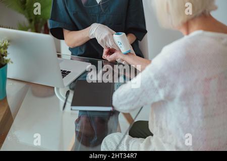 Krankenschwester, die die Gesundheit einer älteren Frau im Wohnzimmer überprüft Stockfoto