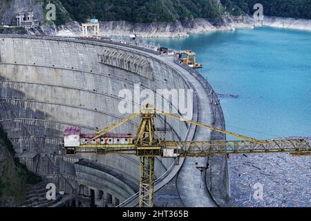 Das größte Wasserkraftwerk im Kaukasus, das sich am Fluss Inguri befindet. Blick auf den Damm und den Stausee mit türkisfarbenem Wasser. Gegen die Stockfoto