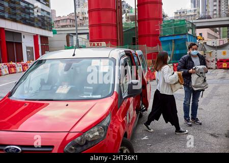 Hongkong, China. 25.. Februar 2022. Ein Paar steigt in der Yau Ma Tei Designated Clinic in Hongkong aus einem Covid-19-Taxi aus.in Hongkong nehmen die Fälle von Covid-19 weiter zu und überschreiten die 10.000-Marke. (Foto von Emmanuel Serna/ SOPA Images/Sipa USA) Quelle: SIPA USA/Alamy Live News Stockfoto