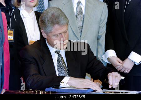 Washington, DC, USA. 12.. März 1996. US-Präsident Bill Clinton unterzeichnet das Helms-Burton-Gesetz zur Verschärfung des kubanischen Embargos im Gebäude des Alten Exekutivbüros des Weißen Hauses am 12. März 1996 in Washington, D.C. um den Präsidenten herum sind Familienmitglieder von Piloten der Brüder der Rettung, die getötet wurden, als ihre Flugzeuge von kubanischen Kampfflugzeugen abgeschossen wurden. Stockfoto