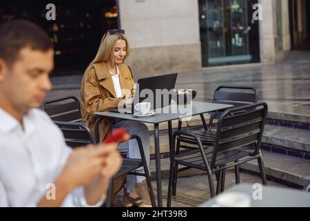Eine fokussierte Frau arbeitet draußen am Laptop Stockfoto
