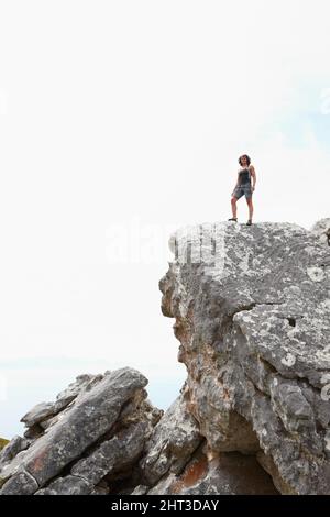 Die Welt hinter sich lassen. Ein Felskletterer, der auf einer Klippe steht. Stockfoto