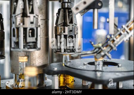 Die automatische Ausrüstung bringt Verschlüsse auf Flaschen mit alkoholischen Getränken Stockfoto