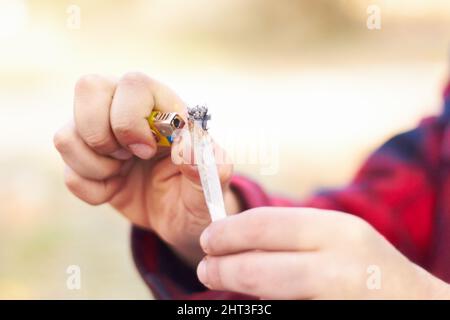 Alles hat ein Tor. Aufnahme eines Mannes, der ein großes Marihuanagelenk zünden soll. Stockfoto