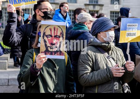 26.. Februar 2022: Ukrainische Staatsbürger und pro-ukrainische Anhänger versammeln sich in Whitehall, um gegen die russische Invasion in der Ukraine zu protestieren. London, Großbritannien. Im Bild: Eine Frau hält ein Plakat mit einem Bild des russischen Präsidenten Putin mit einem blutigen Handdruck auf seinem Gesicht. Stockfoto