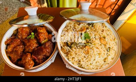 Kochtopf aus gebratenem Reis mit Gemüse und Garnelen und leckerem Chili-Huhn auf dem Tisch Stockfoto