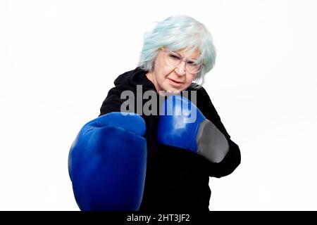 Ältere Frau mit Boxhandschuhen und Wache Pose auf weißem Hintergrund Stockfoto